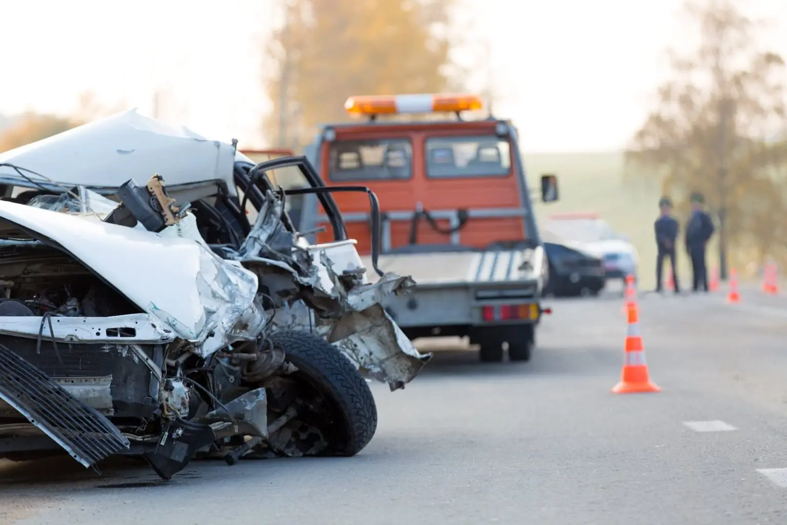 Dos coches chocados en una carretera con un vehículo de emergencia al fondo